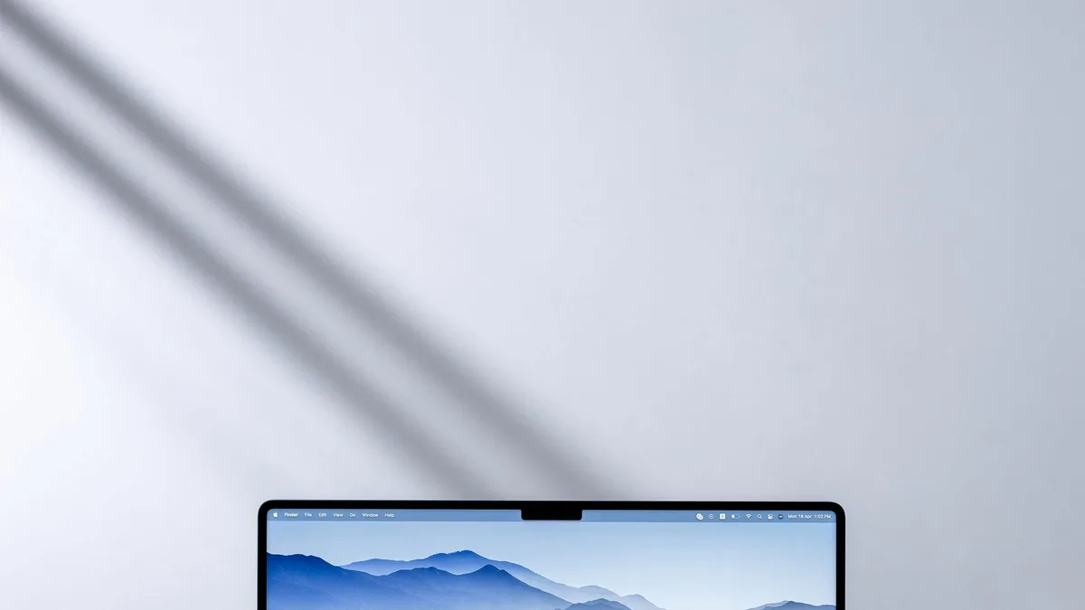 Laptop mit Bergpanorama-Hintergrundbild und Kopfhörern auf einem Schreibtisch