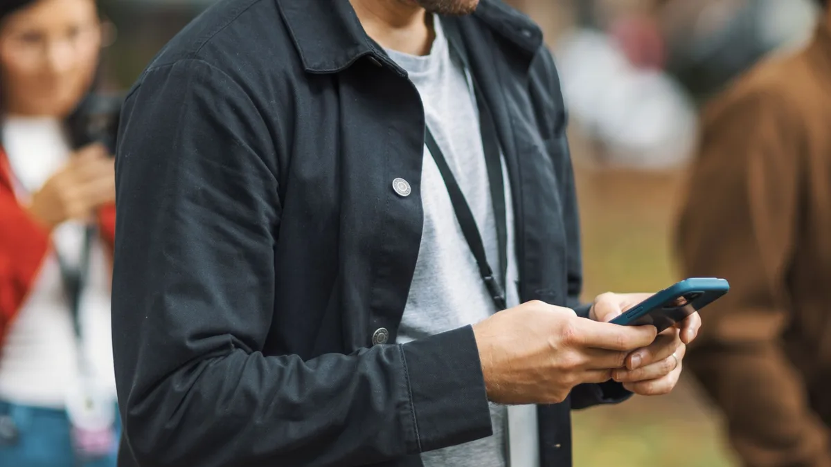 Mann blickt im Vorbeigehen auf sein Smartphone