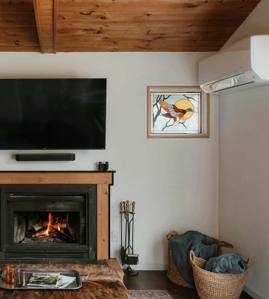 Gemütliches Wohnzimmer mit Kamin und wandmontiertem Fernseher, Bildschirm ausgeschaltet
